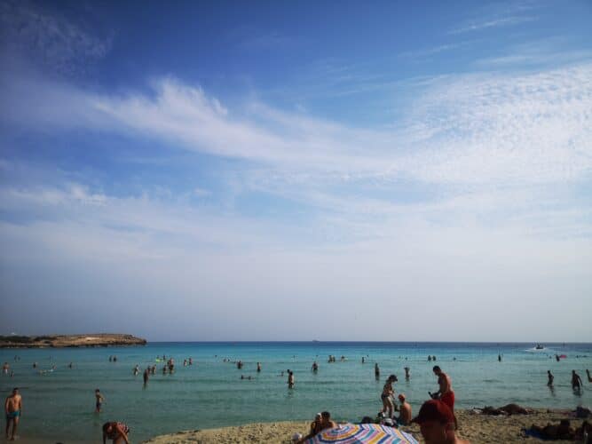 Beach with clear blue water and people sunbathing